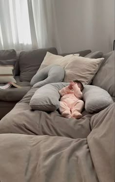 a baby sleeping on top of a giant bean bag chair in the middle of a living room