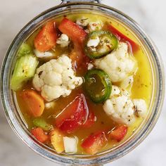 a glass bowl filled with vegetable soup on top of a table