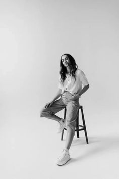 a black and white photo of a woman sitting on a stool