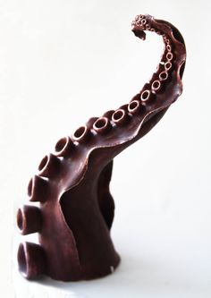 a chocolate sculpture of an octopus on a white surface with its mouth open and tongue out