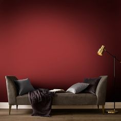 a living room with a couch, lamp and red wall