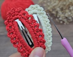 two crocheted hair clips are being held by someone's hand with a pair of scissors