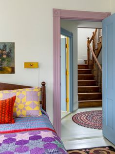 there is a bed with colorful blankets and pillows in the room next to the stairs