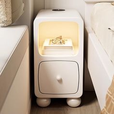 a white night stand with a light on it next to a bed in a small room