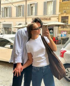 a man and woman standing next to each other in front of a building with umbrellas