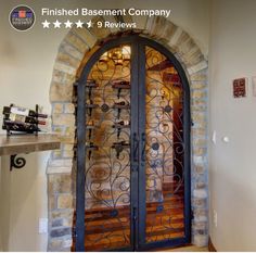 an arched door in the entry way to a home with stone walls and doors that have iron bars on them