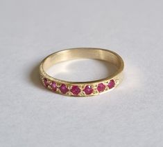 Handmade delicate 14k gold half eternity ring, stoned with 7 beautiful red Rubies.  This Gold Ruby ring is beautiful alone or stacked together with other rings and is colorful and pretty on your finger.  The price is for one ring. Materials: The red Ruby band ring is available in nickel free, 14 karat gold plating over a brass or silver base.  Can be also ordered in solid sterling silver, 9k or 14k solid gold.  A perfect engagement ring or just a beautiful gift for you. Dimensions: The ring widt Yellow Gold Ruby Eternity Band As Gift, Red Half Eternity Band As A Gift, Ruby Half Eternity Band Gift, 14k Gold Eternity Band With Gemstone As Gift, Ruby Half Eternity Band As A Gift, Ruby Stackable Round Band Promise Rings, Stackable Ruby Ring In 14k Gold With Round Band, Ruby Half Eternity Ring As Gift, Red Half Eternity Ring For Gift