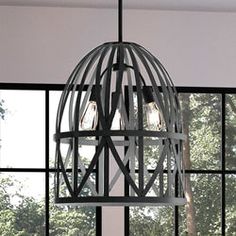 a light fixture hanging from the ceiling in front of a large window with trees outside