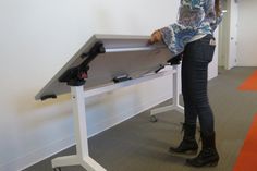 a woman standing in front of a white table with a laptop on top of it