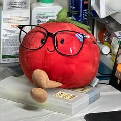 a stuffed tomato with glasses on top of it's head next to other medical supplies