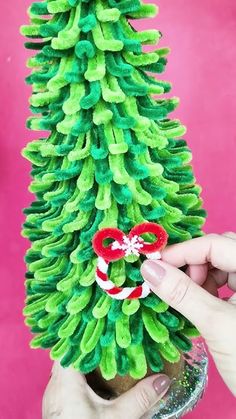 someone is decorating a small christmas tree with green and red decorations on the top