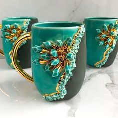 three green mugs with gold decorations on them