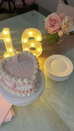 a heart shaped cake sitting on top of a table next to some plates and flowers