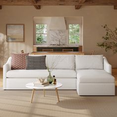 a living room with a white couch and coffee table in front of a kitchen area