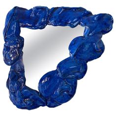 a blue sculpture is shown in the shape of a heart, with an oval mirror behind it