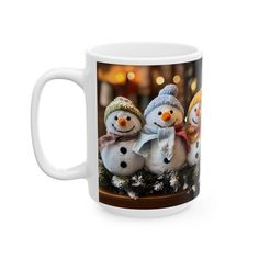 a coffee mug with three snowmen wearing hats and scarfs on top of it