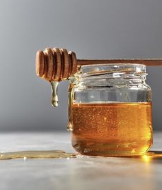 honey dripping from a wooden spoon into a jar