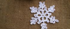 a crocheted snowflake sitting on top of a piece of burlock