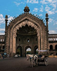 a horse drawn carriage standing in front of an old stone building with arches and pillars