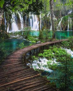 a wooden walkway leads to a waterfall in plitunka national park, croatia