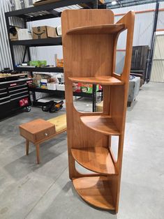 a curved wooden shelf in a warehouse with other items on the floor and shelves behind it