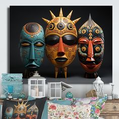 three decorative masks sitting on top of a bed next to pillows and pillowcases