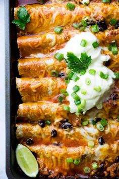 mexican enchilada rolls with sour cream and cilantro on top in a baking dish