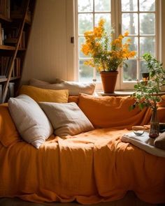 a living room with a couch, bookshelf and yellow flowers in the window