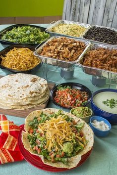 a table topped with lots of different types of tacos and burritos on top of plates