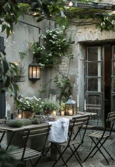 an outdoor dining area with chairs, tables and potted plants on the outside wall