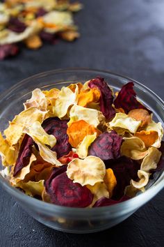 a glass bowl filled with dried flowers on top of a black table next to another bowl