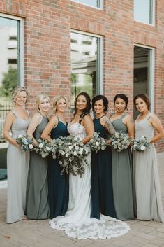 a group of women standing next to each other in front of a brick building holding bouquets