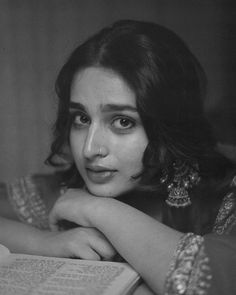 a black and white photo of a woman reading a book with her hands on her chin