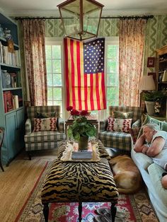 a living room filled with furniture and an american flag hanging from the window above it