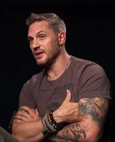 a man with grey hair and tattoos on his arm is looking at the camera while holding his arms crossed