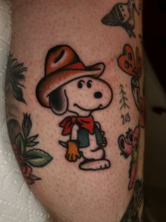 a man's leg with a tattoo of a cartoon dog wearing a hat and scarf