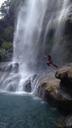 a person jumping into the water from a waterfall