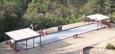 an aerial view of a bus stop in the middle of a wooded area with flags on it