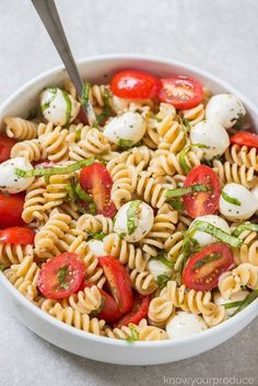 a pasta salad with tomatoes, mozzarella and basil