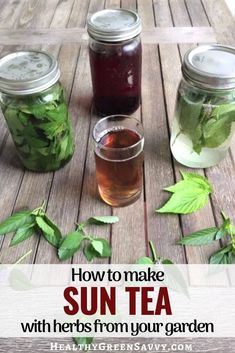 three jars filled with tea sitting on top of a wooden table next to green leaves