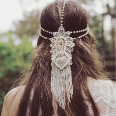 the back of a woman's head wearing a hair piece with beads and chains on it