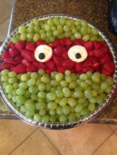 a bowl filled with grapes and strawberries in the shape of a face