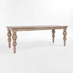 an old wooden table with turned legs on a white background in front of a plain backdrop