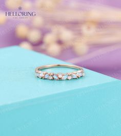 an image of a ring with stones on the front and back side, sitting on top of a blue box