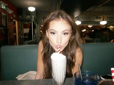 a woman blowing on a straw with a drink in her hand