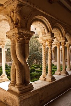 an old building with columns and plants in the background