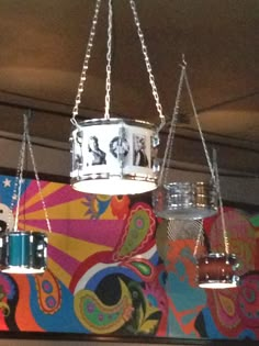 a drum is hanging from the ceiling in front of a colorful wallpapered background