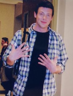 a man standing in front of a mirror holding his hands out to the side while wearing a plaid shirt