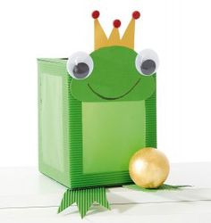 a paper frog with a crown on its head next to an apple