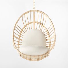 a hanging chair made out of wicker with a white cushion